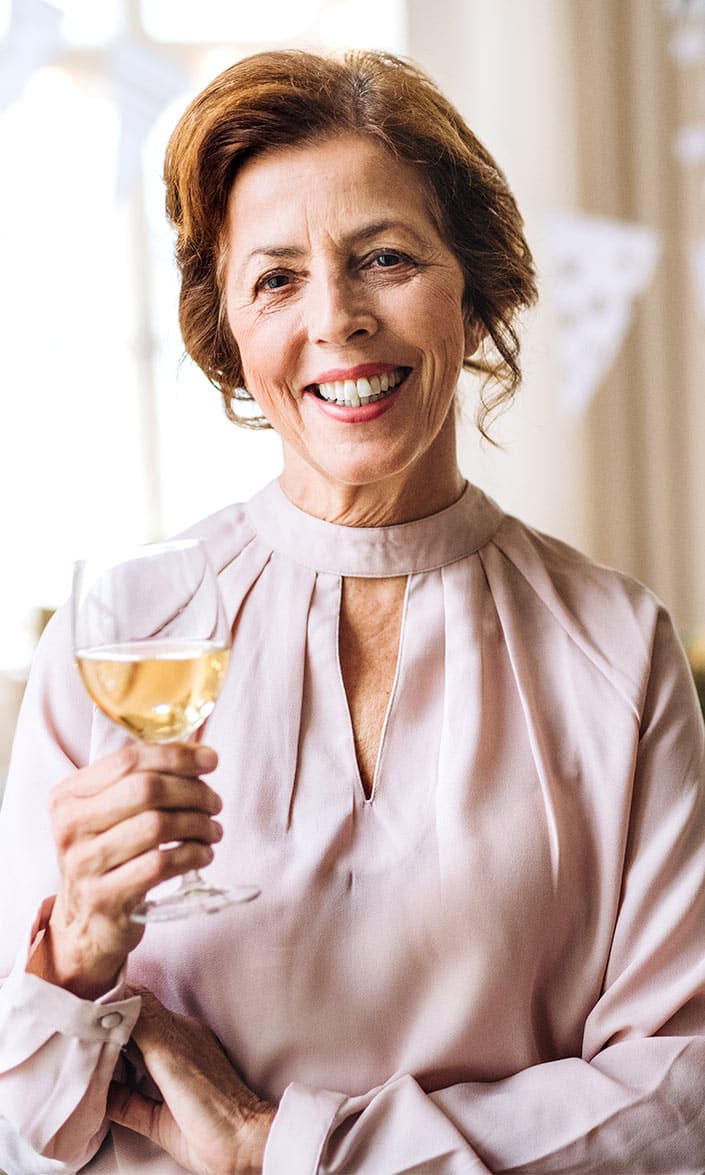 senior woman holding a glass of wine at an adore social event