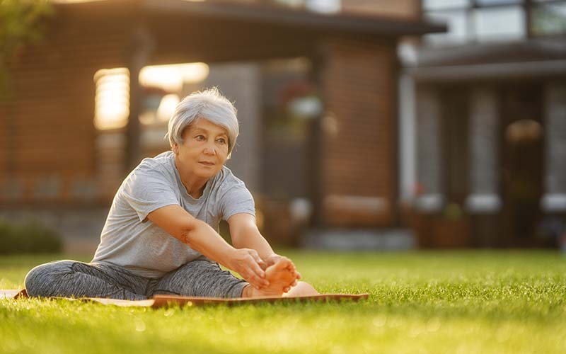 mature woman doing stretch exercises on lawn for breast cancer prevention