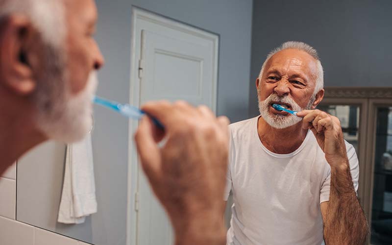 elderly man brushing his teeth