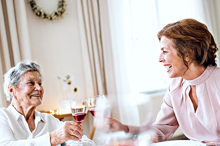 two elderly women drink wine at an adore social event after senior placement services