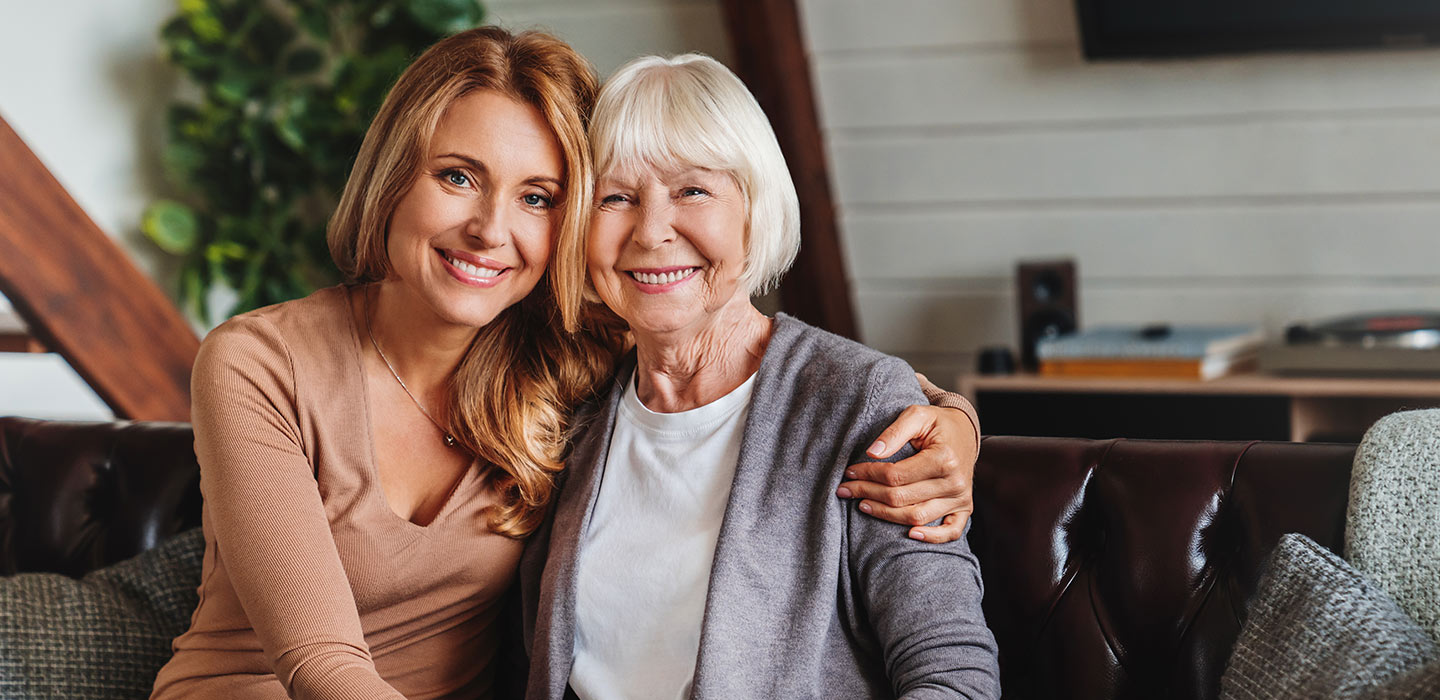 daughter sits with elderly mom on couch to highlight senior placement services