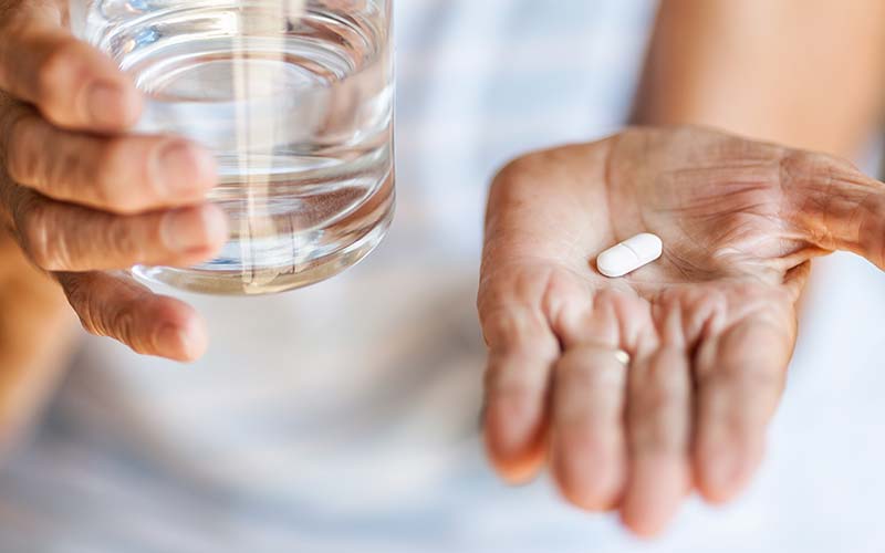 close up of senior woman taking medication while home for the holidays