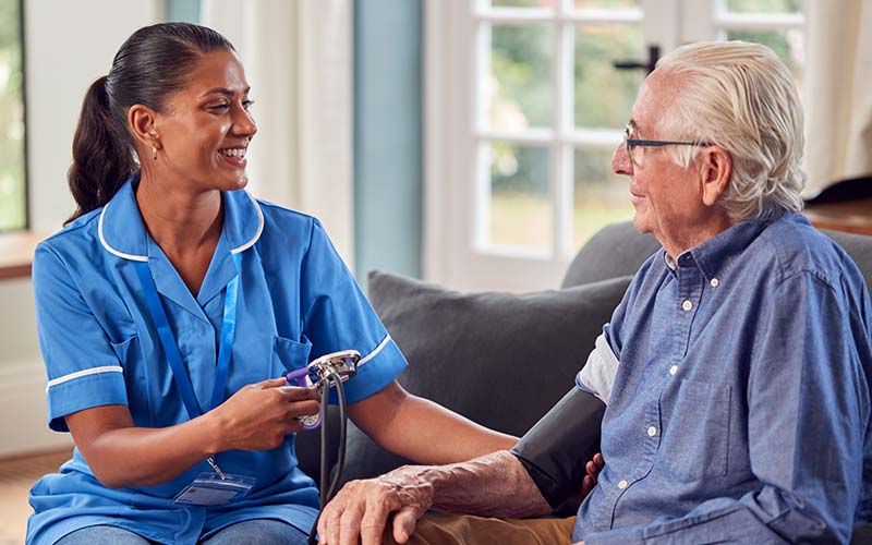 caregiver checking out senior man's blood pressure