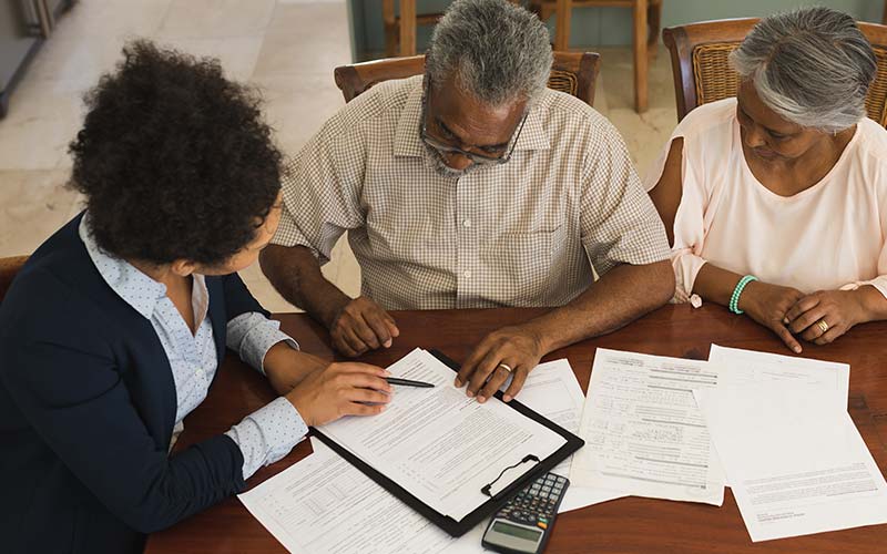 senior real estate specialist helping senior couple with complicated documents