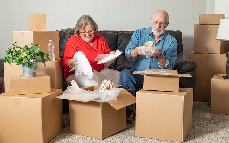 a senior couple packing boxes for a move to downsize their home