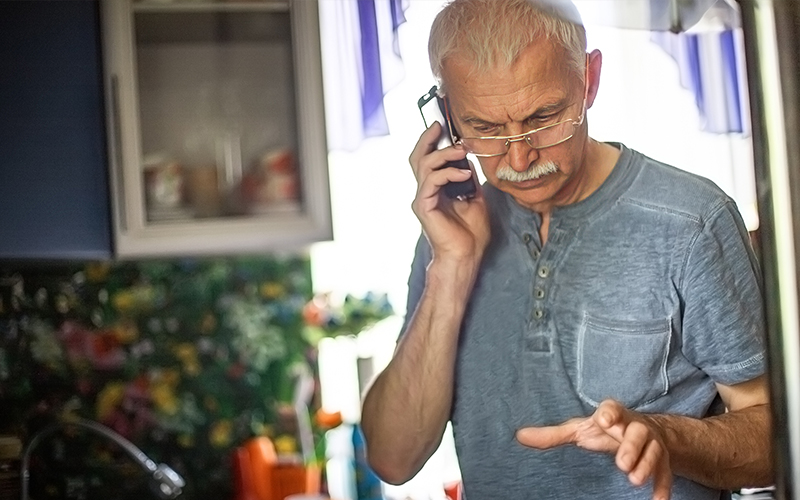 elderly man on phone calling a car service