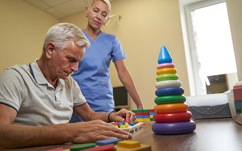 a memory care nurse watches a senior man with a memory game
