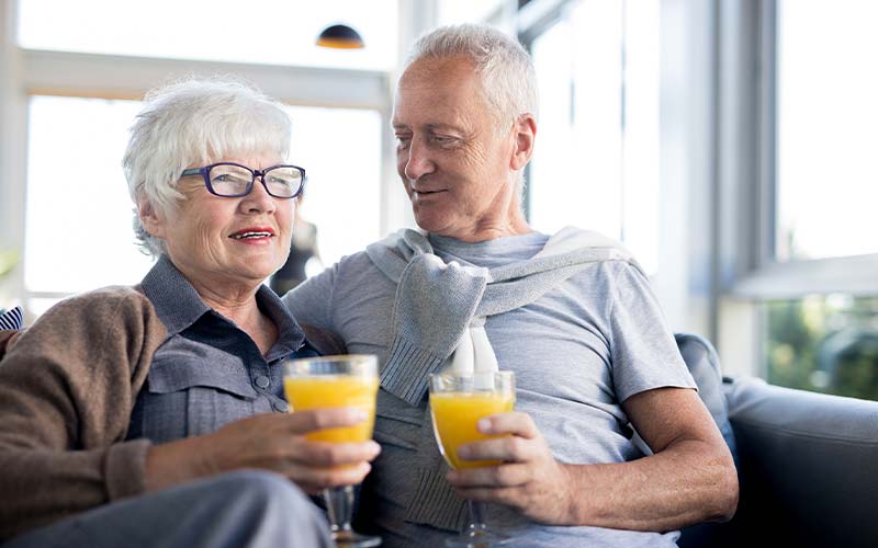 a senior couple enjoy mimosas at their independent living community room