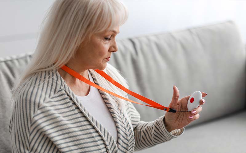 a senior woman holds a call button device around her neck that can get her fast help and help prevent elder abuse
