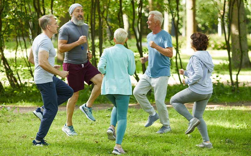 group of active seniors enjoying the summer working out together in a park