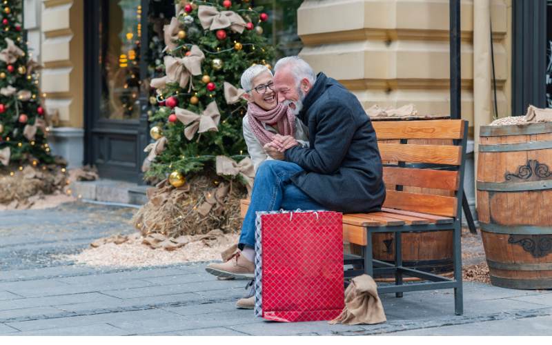 senior couple sit on a bench after shopping during the holiday season