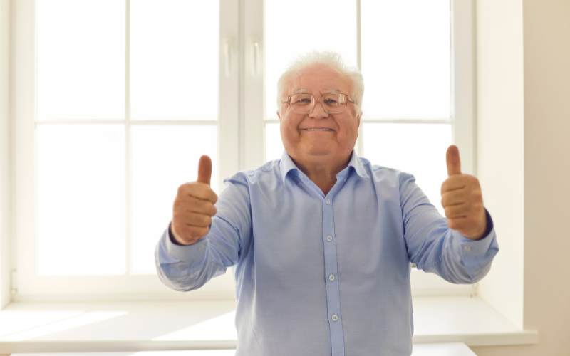a senior man gives enthusiastic thumbs up at his senior living quality care