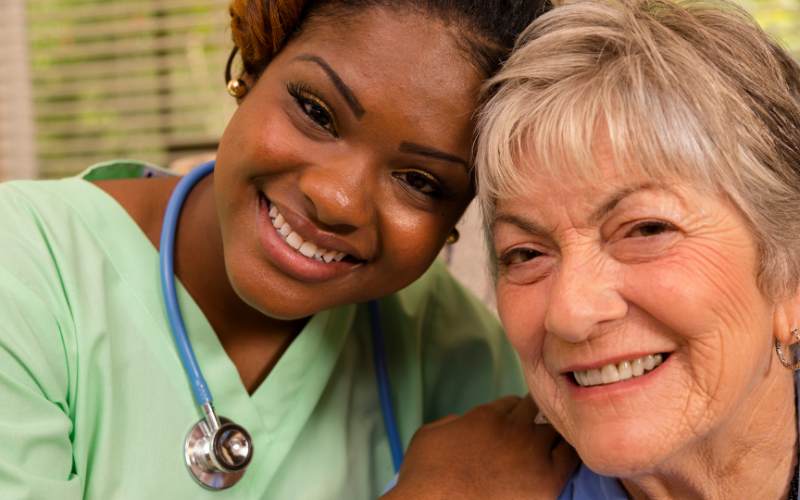 a female nurse and an elderly woman smile at the camera with a better understanding of medicare and assisted living